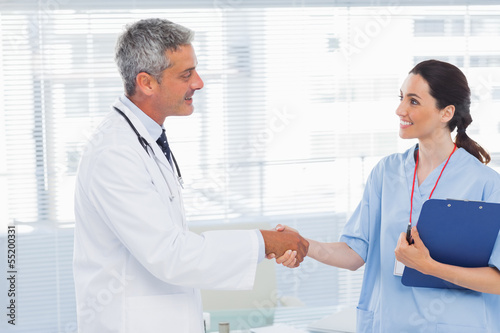 Smiling doctor shaking hands with nurse