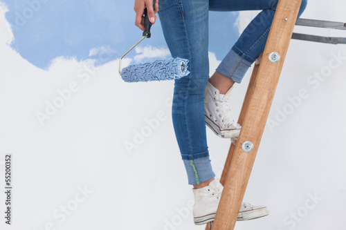 Woman holding paint roller on ladder