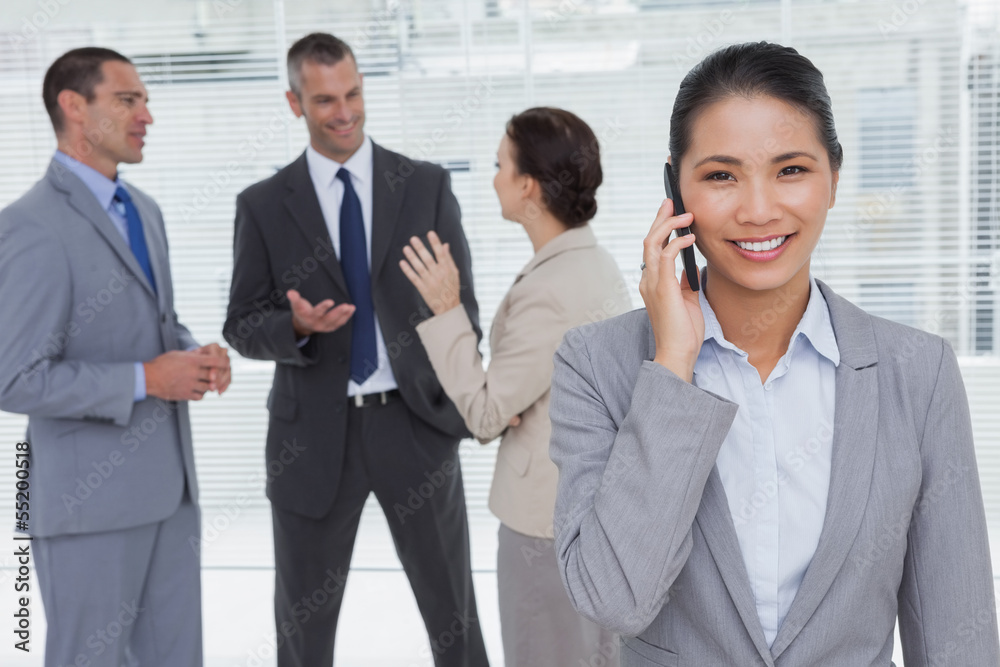 Businesswoman on the phone while colleagues talking Businesswoman on the phone while colleagues talking