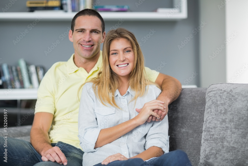 Smiling young couple sitting on their couch Smiling young couple sitting on their couch