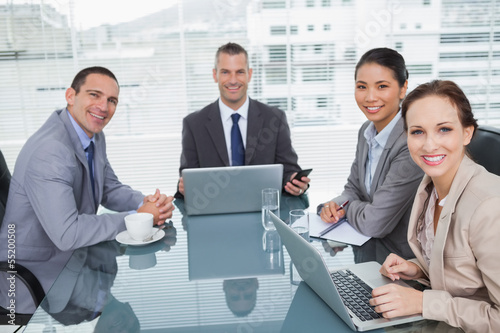 Smiling business people working together with their laptop