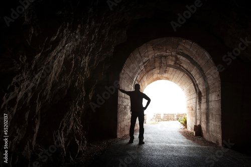 Young man stands relaxed in dark tunnel