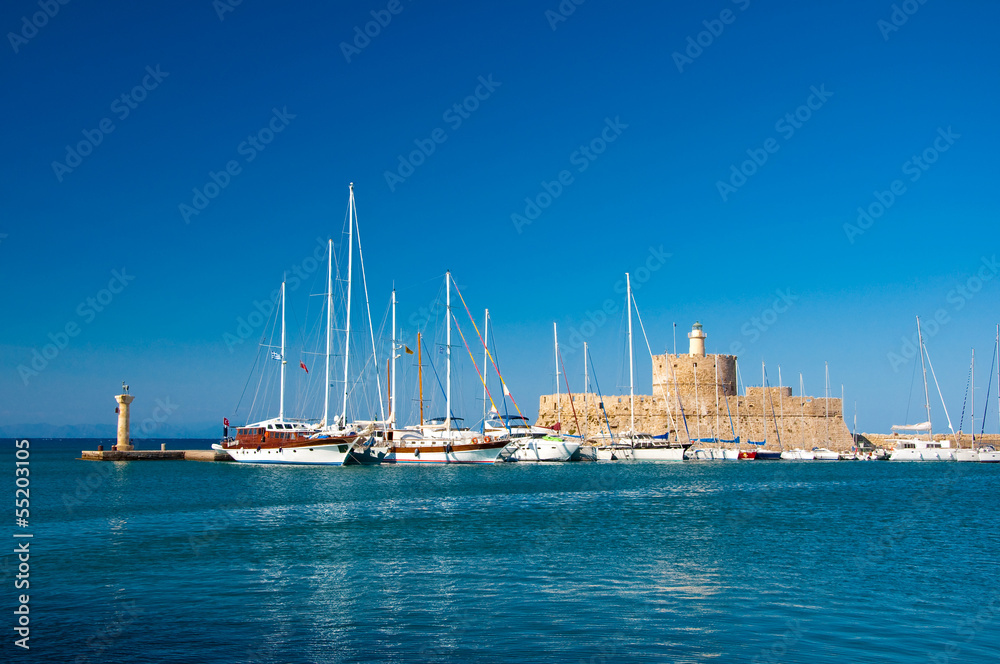 Yachts and old lighthouse in the harbor of Rhodes,Greece.