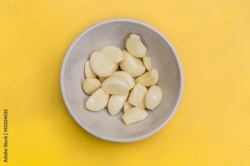 fresh peel garlic in a bowl yellow background