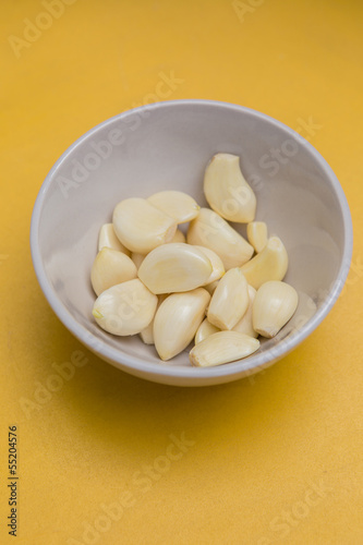 fresh peel garlic in a bowl yellow background