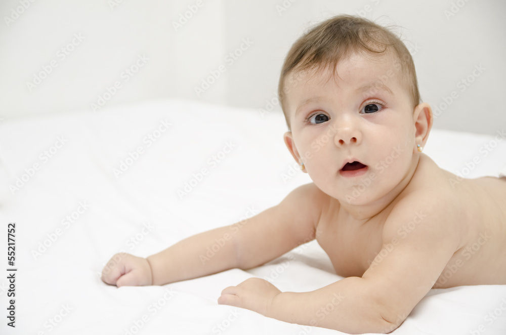 Cute baby on bed in home bedroom.