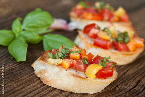 Bruschetta with tomato, garlic, basil on wooden board