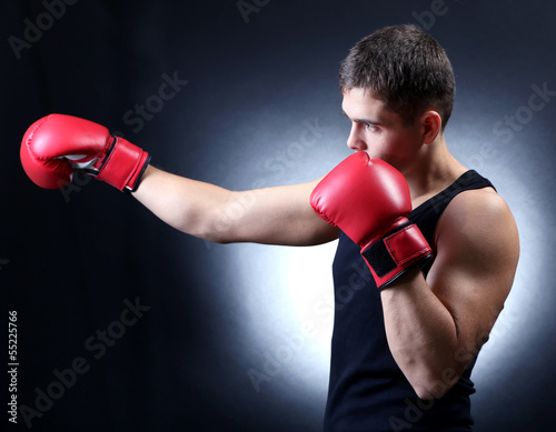 Handsome young muscular boxer on dark background