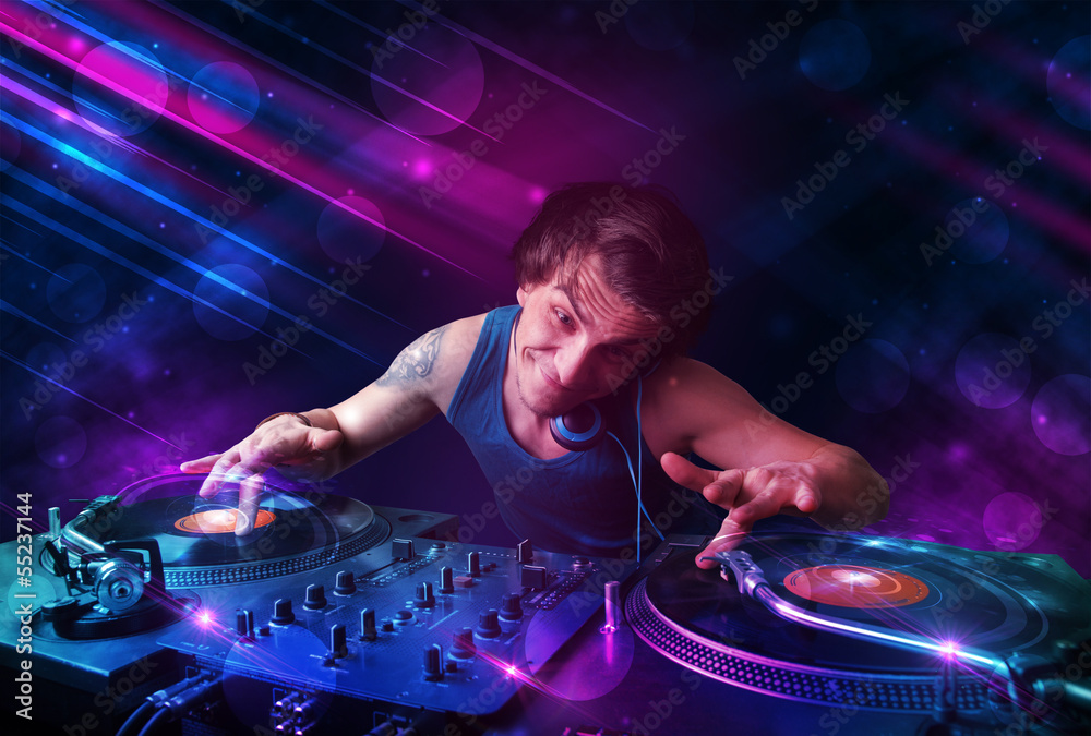 Young DJ playing on turntables with color light effects