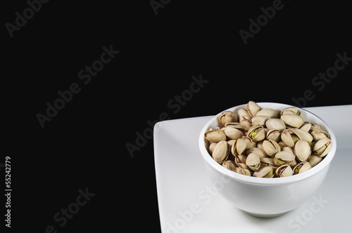 Bowl of pistachios on white plate.