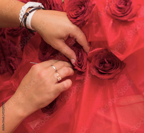 Female hands sew roses to a fabric