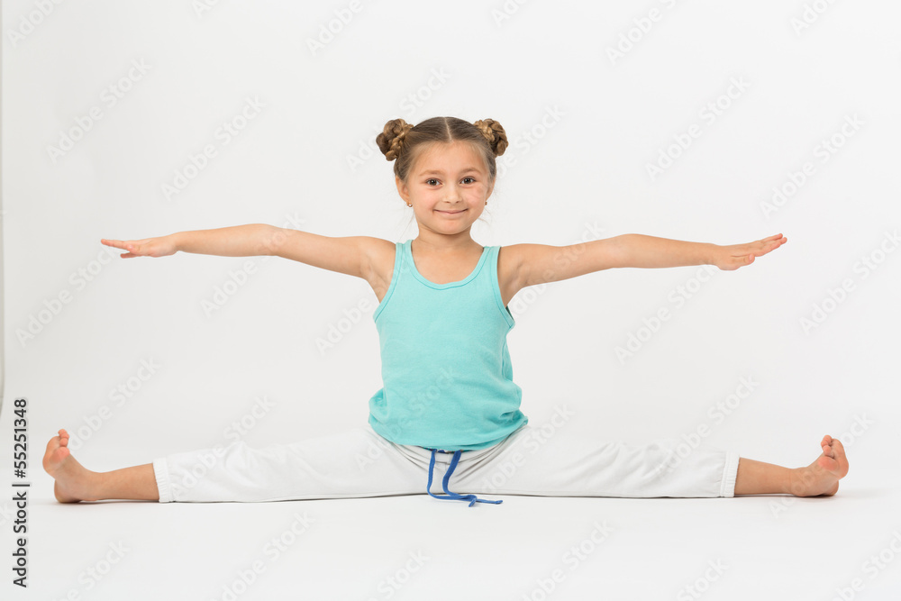 A girl makes gymnastic exercise sitting on splits