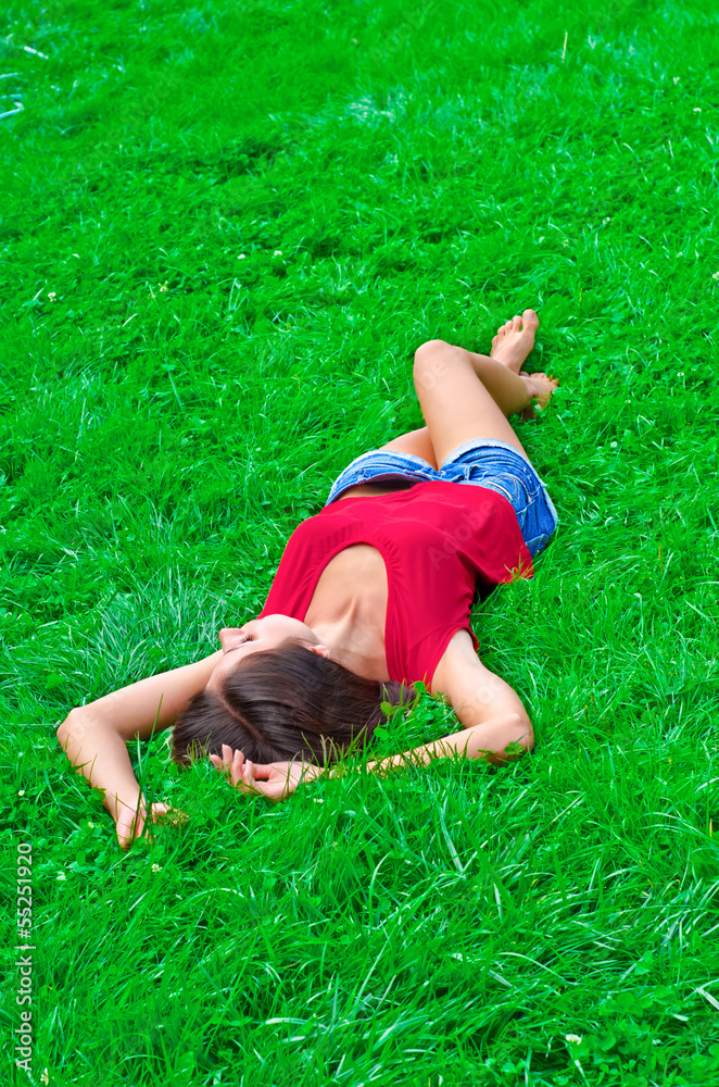 Beautiful young slim woman relaxing lying on the grass Beautiful young slim woman relaxing lying on the grass