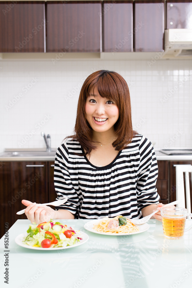beautiful asian woman eating in the kitchen