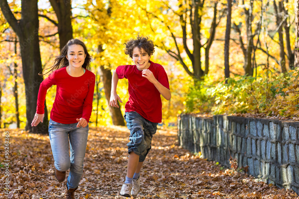 Girl and boy running, jumping in park