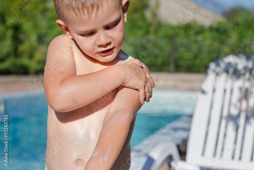 Young boy carefully applying sunscreen