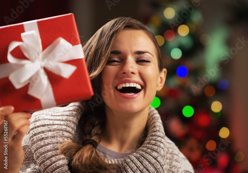 Happy woman looking out from present box near christmas tree