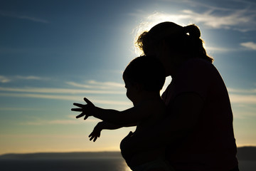 Silhouettes - woman & child playing against sky
