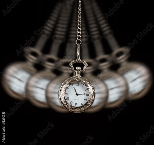 Pocket watch swinging on a chain black background
