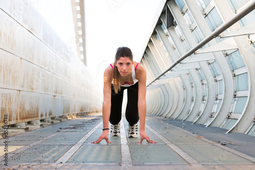 Beautiful young woman getting ready to run on a modern bridge