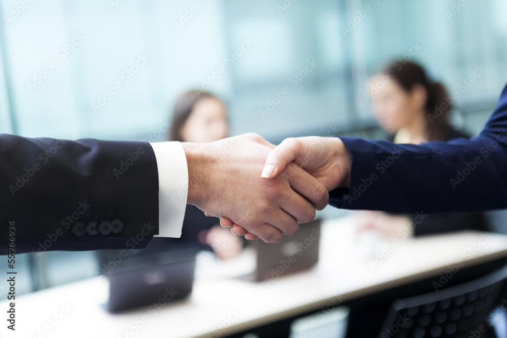 Business handshake and business people at the office Business handshake and business people at the office