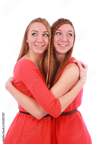 Two girls twins in red dresses hugging isolated on the white
