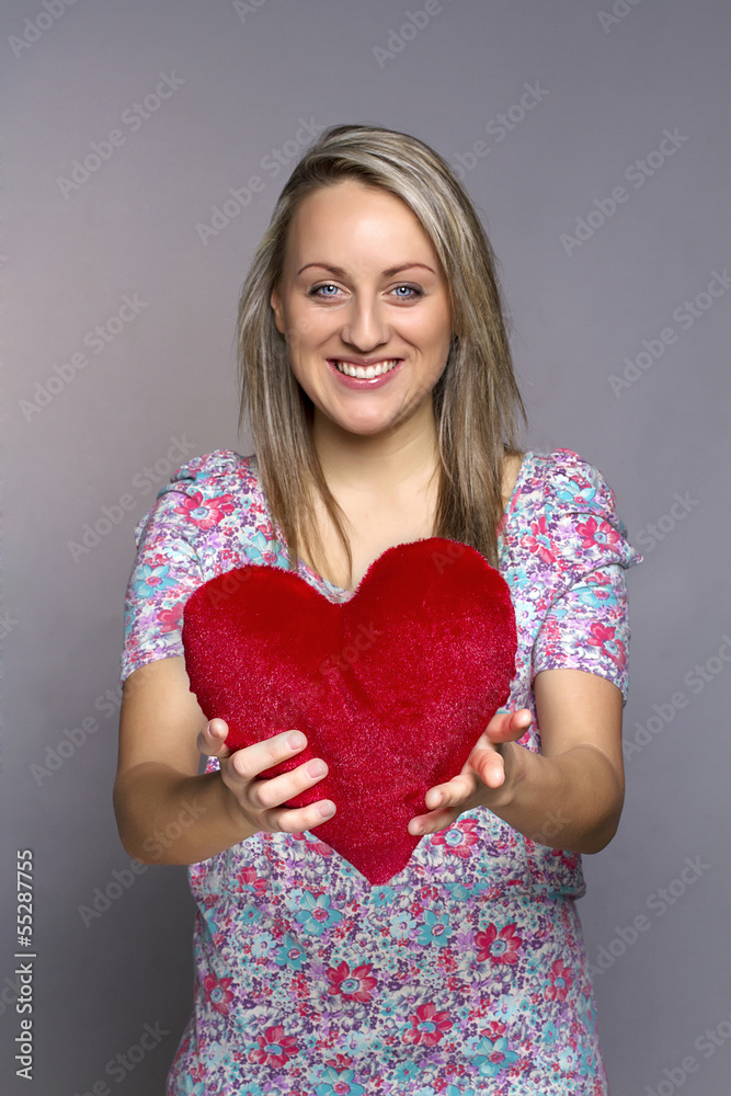 attractive smiling woman on gray background holding a red heart attractive smiling woman on gray background holding a red heart