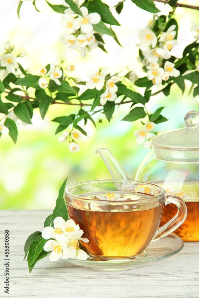 Cup of tea with jasmine, on wooden table, on bright background Cup of tea with jasmine, on wooden table, on bright background