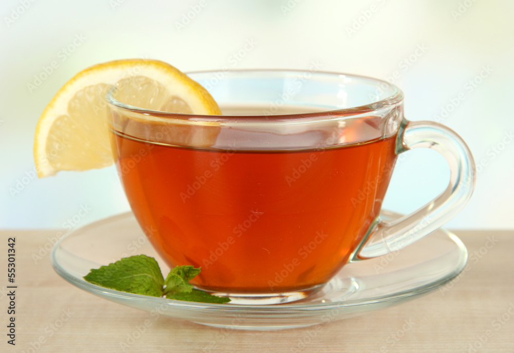 Cup of tea with lemon on table on light background Cup of tea with lemon on table on light background