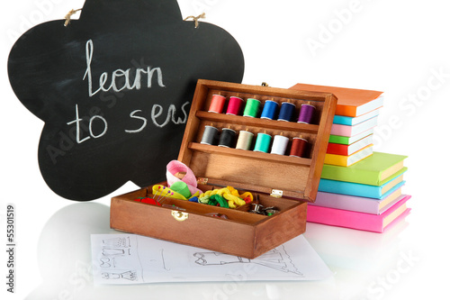 Sewing kit in wooden box and books isolated on white photo