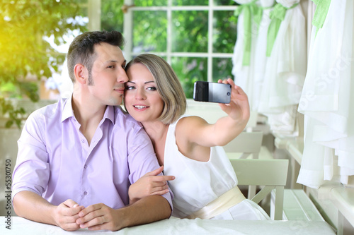 Young couple taking photo with mobile phone in restaurant