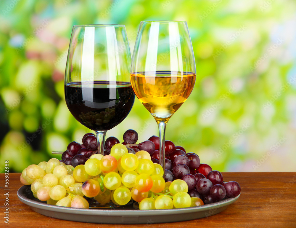 Ripe grapes and glasses of wine, on bright background