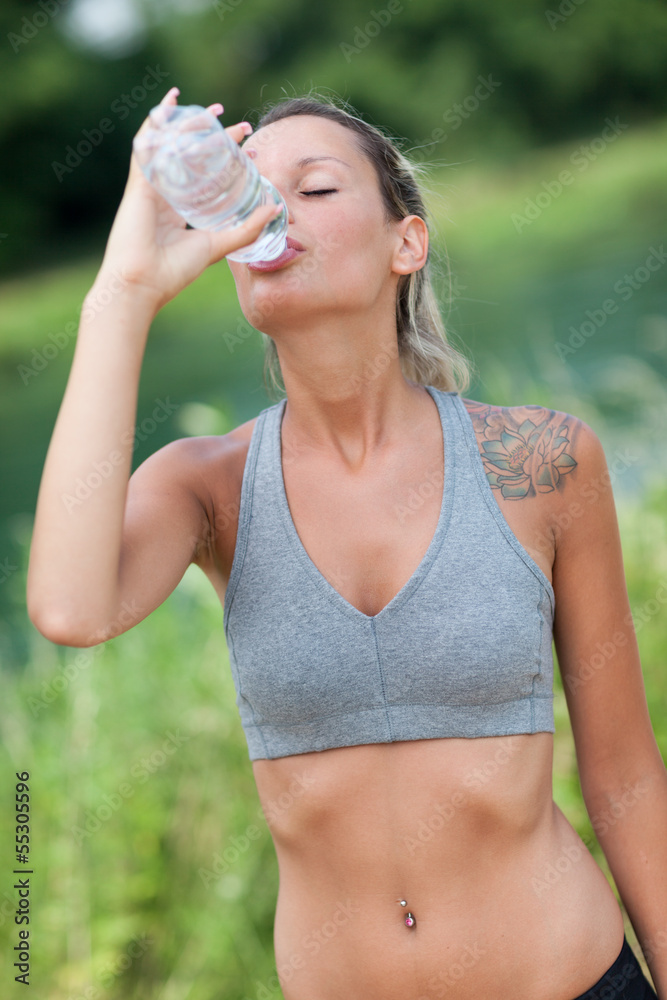 Young woman is drinking water after running session Young woman is drinking water after running session