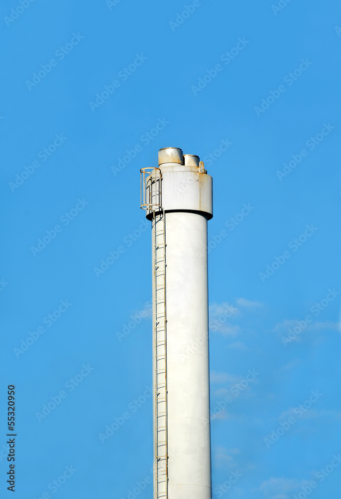 Chimney of industrial plant against blue sky background
