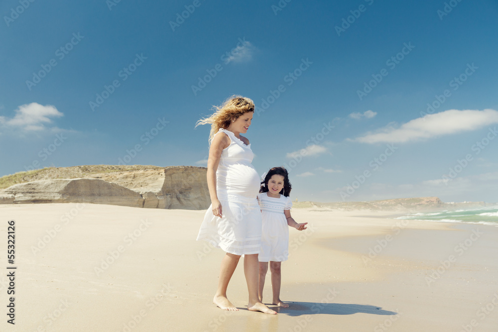 Pregnant woman and her daughter on the beach