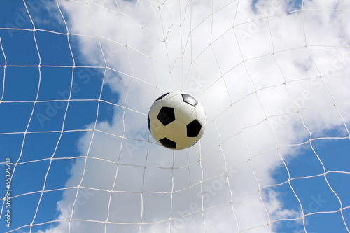 Soccer ball in net on blue sky