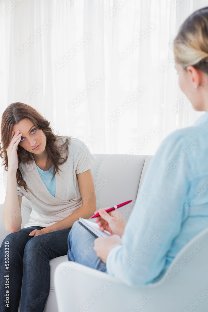 Worried woman sitting with therapist taking notes Worried woman sitting with therapist taking notes