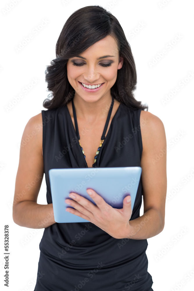 Fototapeta premium Smiling elegant brown haired model typing on tablet