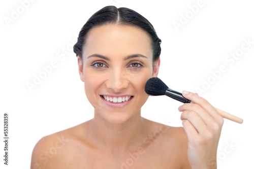 Smiling natural model applying makeup on her face