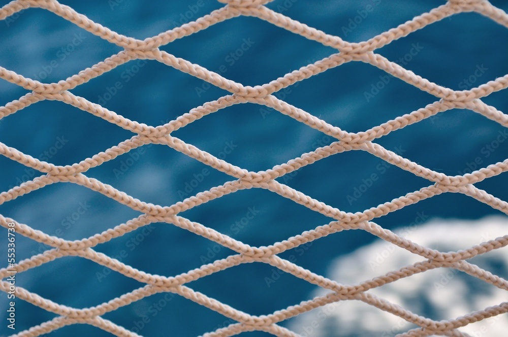 Knitted grid on boat banister with blurred sea on background Knitted grid on boat banister with blurred sea on background