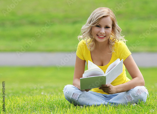 Girl reading book. happy beautiful blonde sitting on grass © Guzel Studio