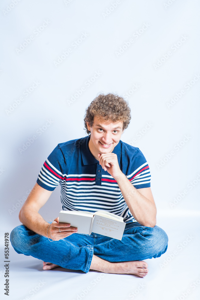 young man sitting on a floor and reading a book. Modern student young man sitting on a floor and reading a book. Modern student