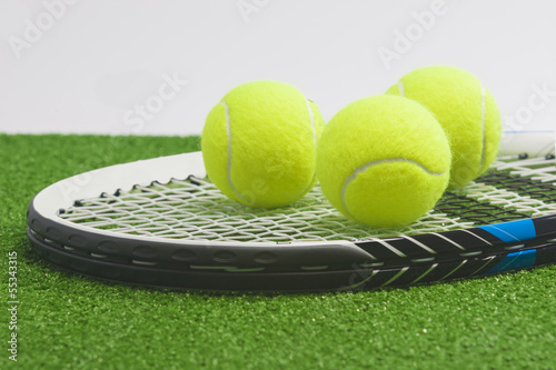 Tennis concept: closeup, tennis racket with balls lies on green © danmorgan12