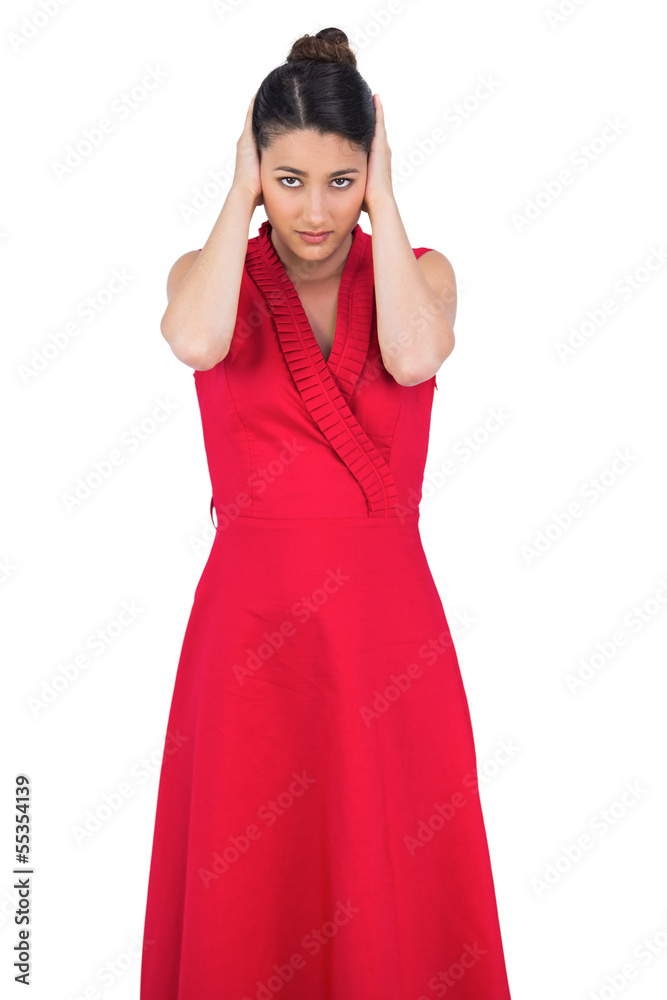 Glamorous model in red dress covering her ears Glamorous model in red dress covering her ears