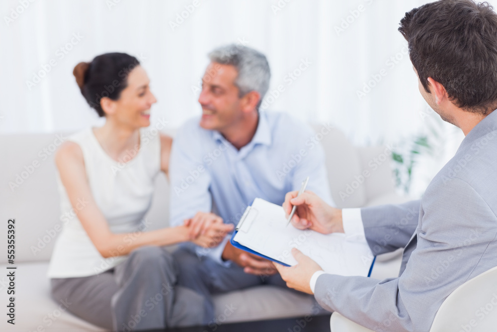 Couple speaking while salesman is holding contract Couple speaking while salesman is holding contract