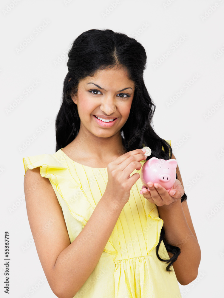 Teenage Girl Putting Money Into Piggy Bank Teenage Girl Putting Money Into Piggy Bank