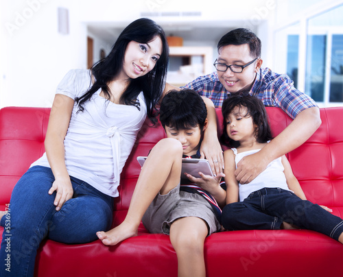 Happy family enjoy relaxing time on red sofa at home © Creativa Images