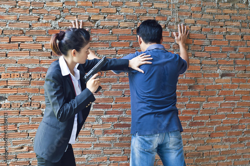 Suspect under arrest by policewoman.