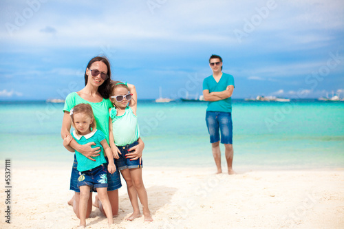Mom with her cute daughters in the foreground and dad in the