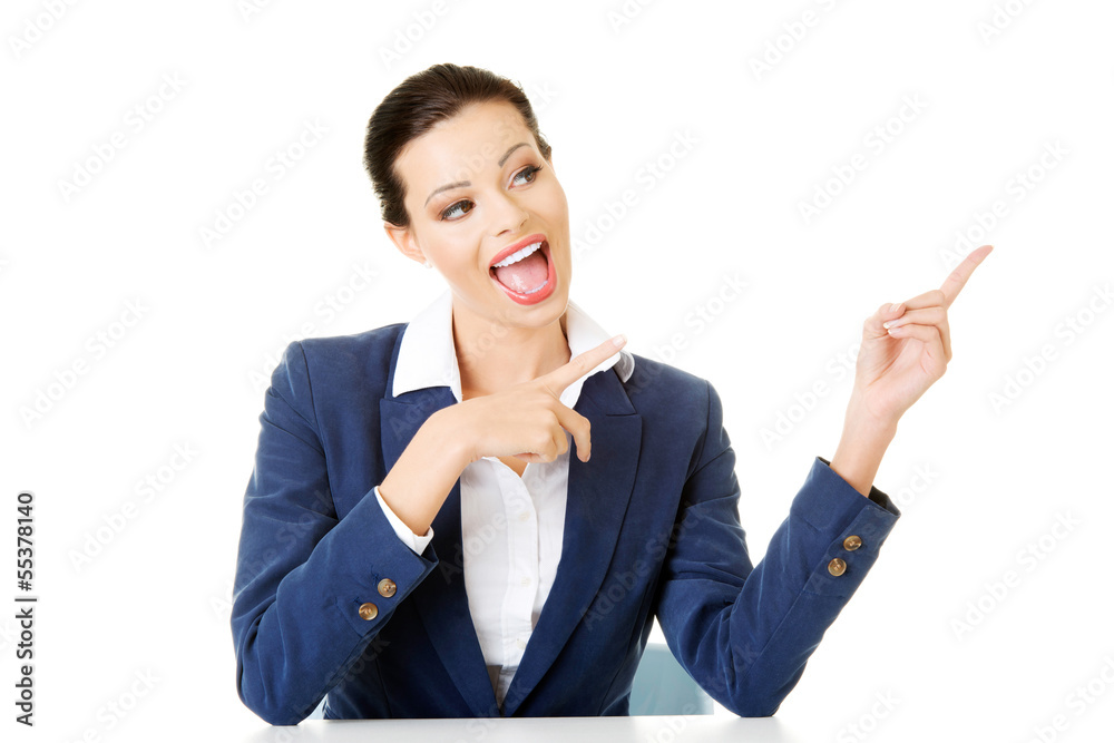 Businesswoman sitting at the desk and pointing on empty copy spa Businesswoman sitting at the desk and pointing on empty copy spa